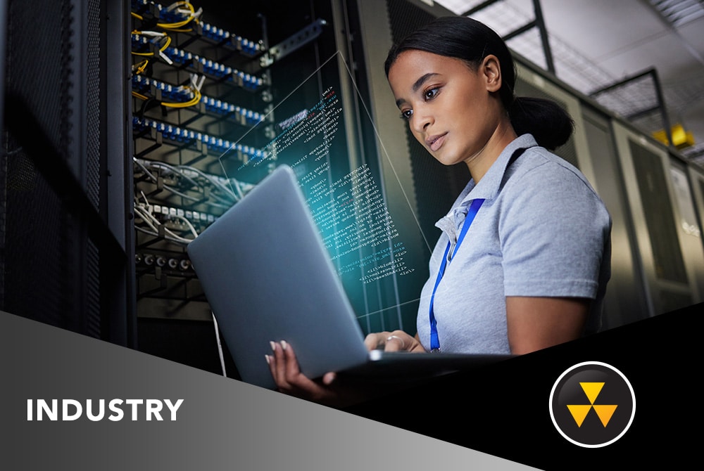 A woman using a laptop in front of a data center rack