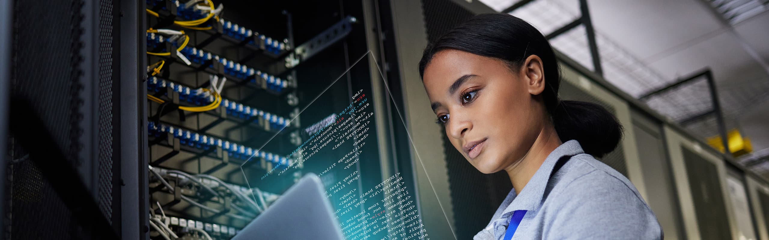 A woman using a laptop in front of a data center rack